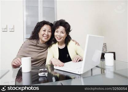 Portrait of two mature women using a laptop smiling
