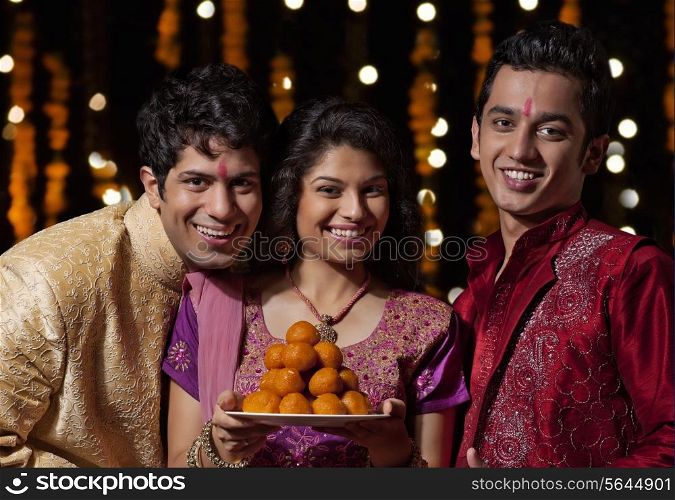 Portrait of two men and a woman holding sweets