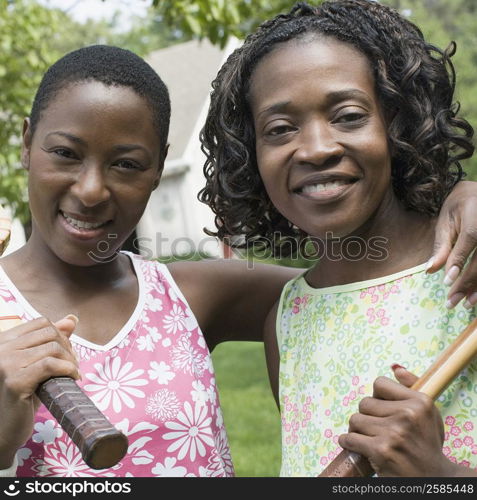 Portrait of two mid adult women holding tennis rackets and smiling