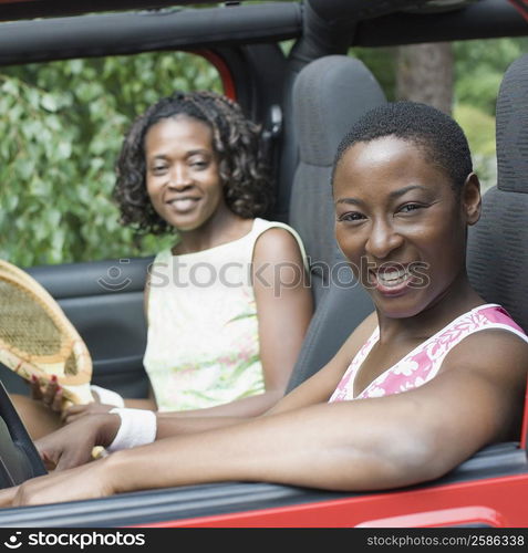 Portrait of two mid adult women smiling in a jeep