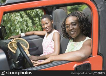 Portrait of two mid adult women smiling in a jeep