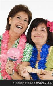 Portrait of two senior women playing ukulele and her friend playing maracas