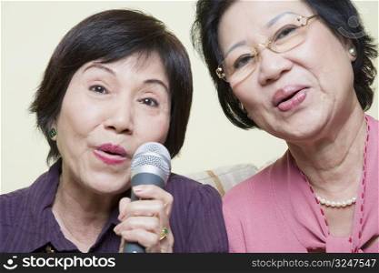 Portrait of two senior women singing into a microphone