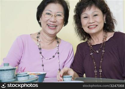 Portrait of two senior women sitting at a table and smiling
