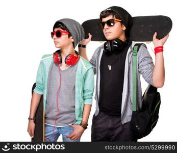 Portrait of two serious boys with skateboards posing in the studio, stylish teens isolated on white background, life of youth