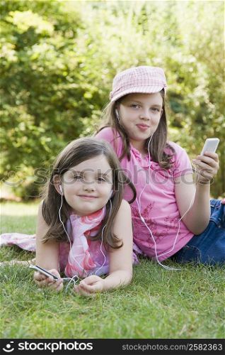 Portrait of two sisters listening to MP3 players in a park