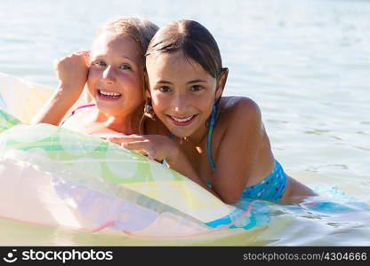 Portrait of two sisters playing with inflatable ring in Lake Seeoner See, Bavaria, Germany