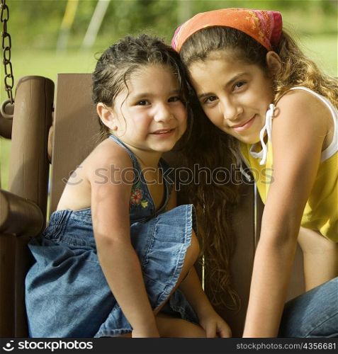 Portrait of two sisters sitting on a swing