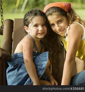 Portrait of two sisters sitting on a swing