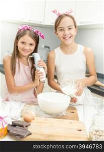 Portrait of two smiling girls cooking pie and making dough