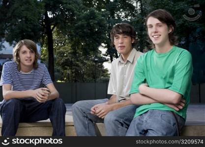 Portrait of two teenage boys sitting with a young man and smiling