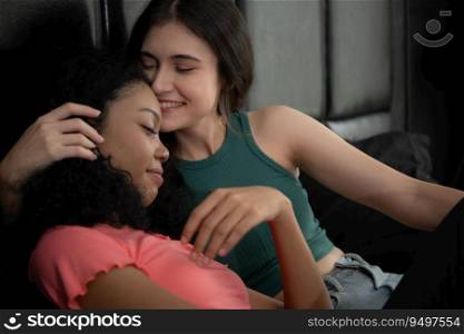 Portrait of two teenage girls sitting on bed in bedroom and kissing her friend on the forehead