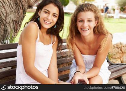 Portrait Of Two Teenage Girls Sitting On Park Bench Together