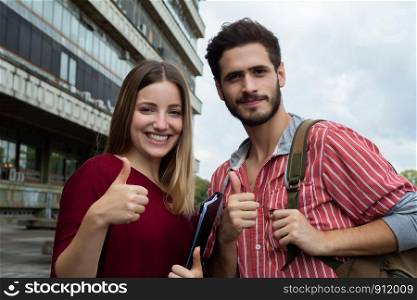 Portrait of two University students showing thumbs up at the building of university. Education concept