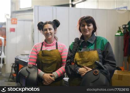 portrait of two welders holding welding masks in their hands and preparing for hard work in a factory. High quality photo. portrait of two welders holding welding masks in their hands and preparing for hard work in a factory
