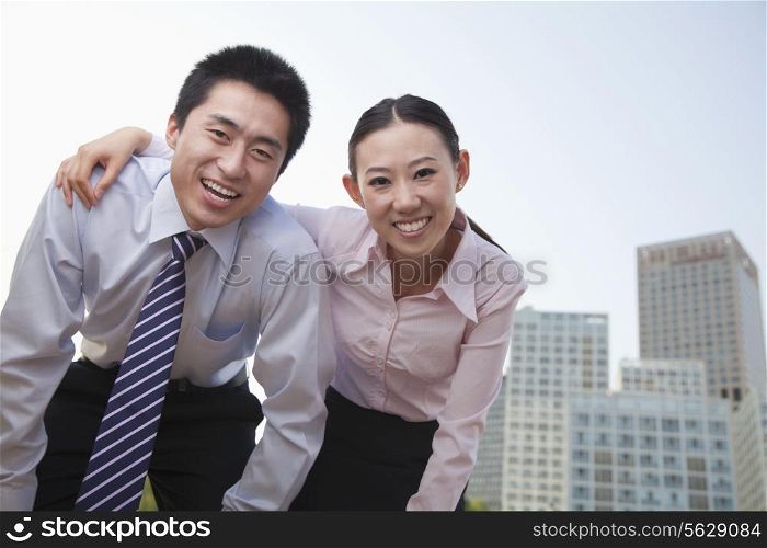 Portrait of two young business people leaning forward, outside in the business district, Beijing