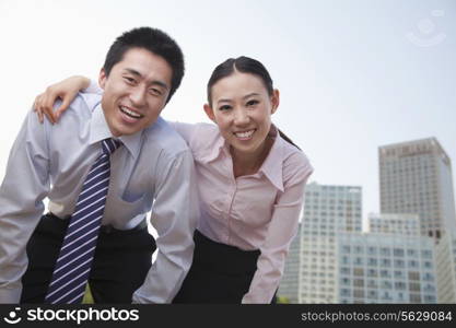 Portrait of two young business people leaning forward, outside in the business district, Beijing