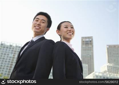 Portrait of two young business people outside in the business district, Beijing, low angle view