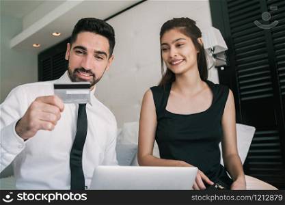 Portrait of two young business people using credit card for online payment at hotel room. Business travel concept.
