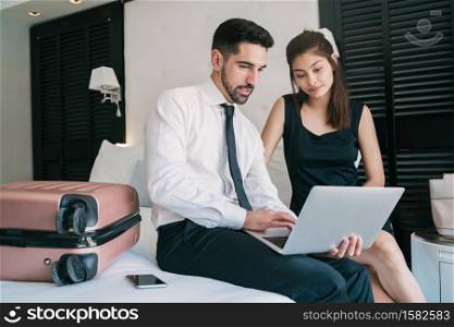 Portrait of two young business people working together on the laptop at the hotel room. Business travel concept.