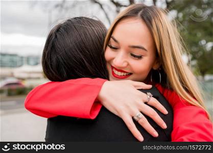 Portrait of two young friends hugging each other outdoors at the street. Lifestyle and friendship concept.