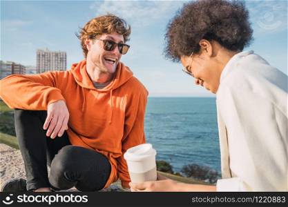 Portrait of two young friends spending good time together and having fun with the sea in the background.
