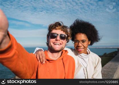 Portrait of two young friends spending good time together and taking a selfie outdoors.