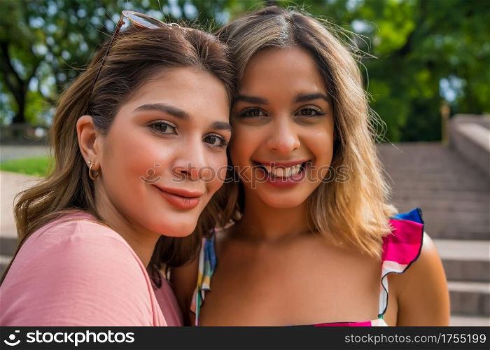 Portrait of two young friends spending good time together while standing outdoors. Urban concept.