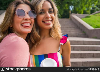 Portrait of two young friends spending good time together while standing outdoors. Urban concept.