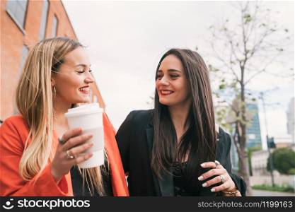 Portrait of two young friends spending good time together while walking outdoors at the street. Lifestyle and friendship concepts.