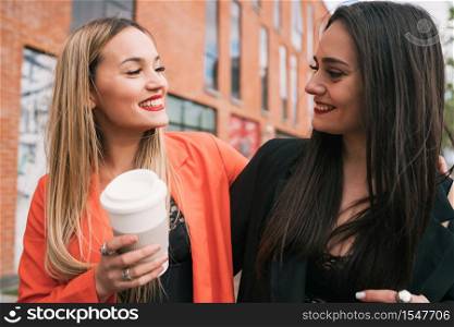 Portrait of two young friends spending good time together while walking outdoors at the street. Lifestyle and friendship concepts.