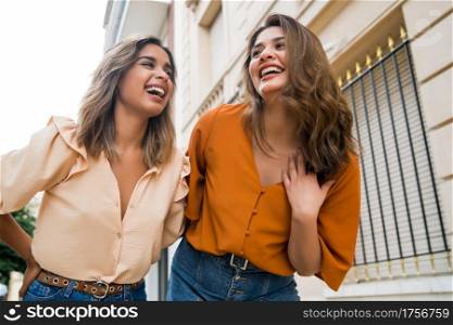 Portrait of two young friends spending good time together while walking outdoors. Urban concept.