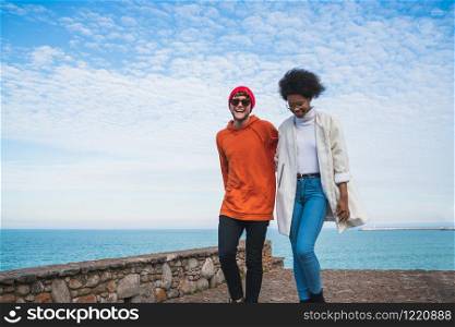 Portrait of two young friends spending some nice time together, walking on coast line and having fun.