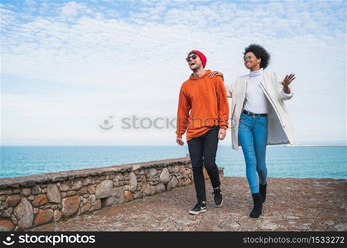 Portrait of two young friends spending some nice time together, walking on coast line and having fun.