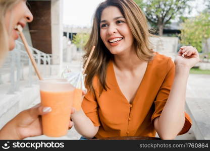 Portrait of two young friends spending time together at a coffee shop outdoors. Urban concept.