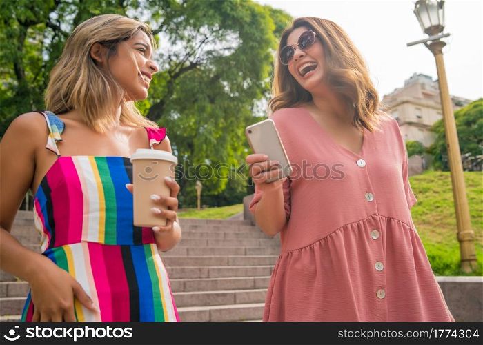 Portrait of two young friends spending time together while walking outdoors. Urban concept.. Two friends walking outdoors.
