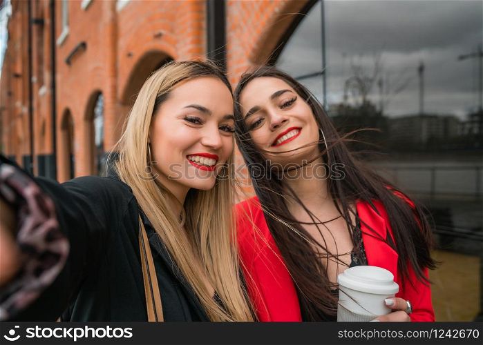 Portrait of two young friends taking a selfie outdoors at the street. Lifestyle and friendship concepts.