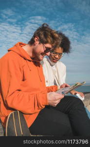 Portrait of two young friends traveling together, with a map and looking for directions. Travel concept.