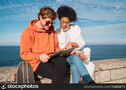 Portrait of two young friends traveling together, with a map and looking for directions. Travel concept.