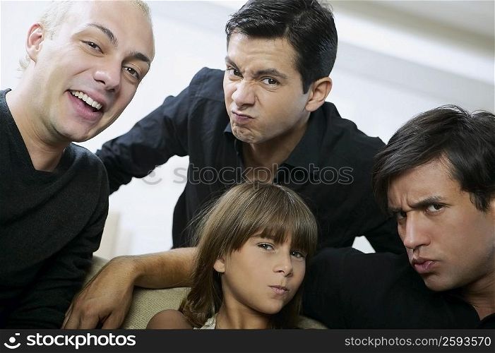 Portrait of two young men and a mid adult man with a girl making faces
