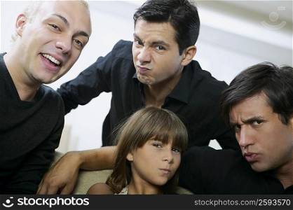 Portrait of two young men and a mid adult man with a girl making faces