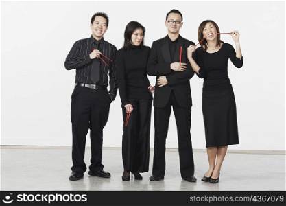 Portrait of two young men and two young women standing and holding chopsticks