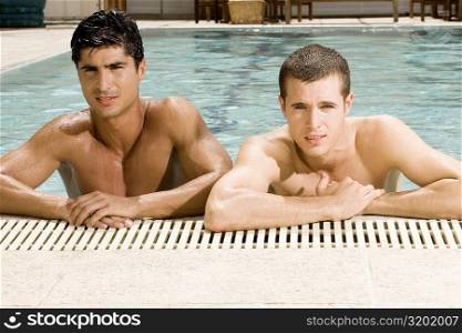 Portrait of two young men at the edge of a swimming pool