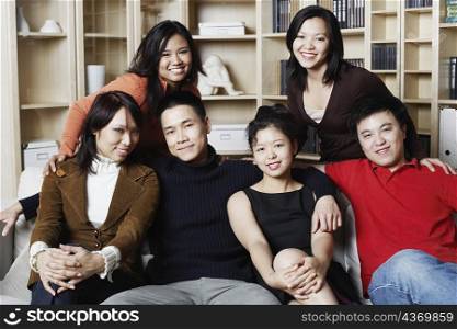 Portrait of two young men sitting together on a couch with four young women smiling