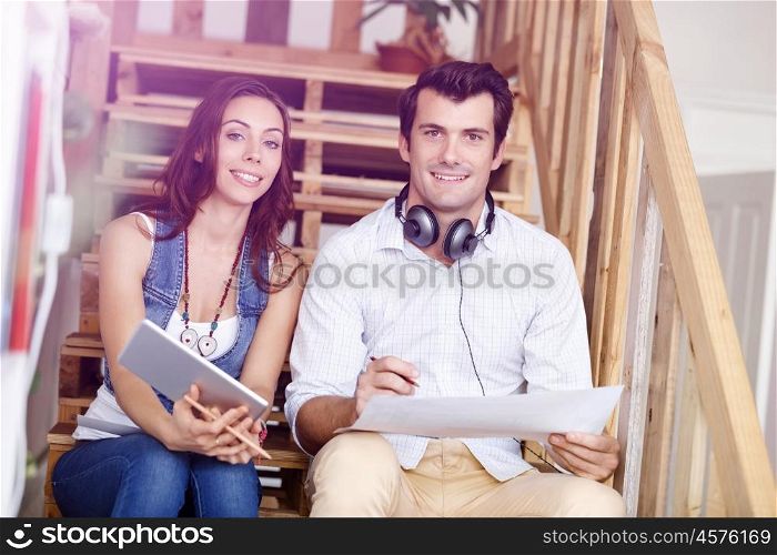 Portrait of two young people sitting at the stairs in office. Portrait of two young people sitting at the stairs in office talking