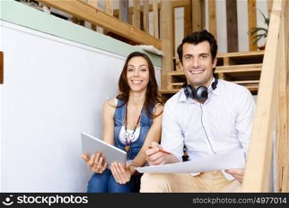Portrait of two young people sitting at the stairs in office. Portrait of two young people sitting at the stairs in office talking