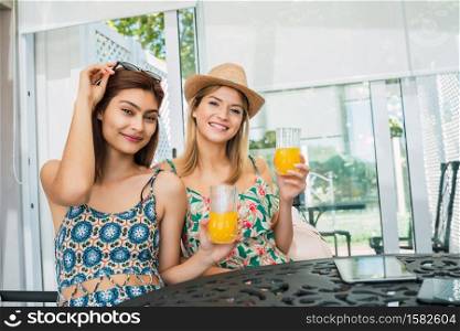 Portrait of two young travelers friends spending some time and drinking juice at the hotel. Travel and lifestyle concept.