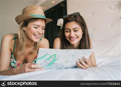 Portrait of two young travelers friends spending some time and organizing their trip at hotel room. Travel and lifestyle concept.