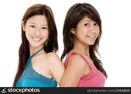 Portrait of two young woman back to back and smiling