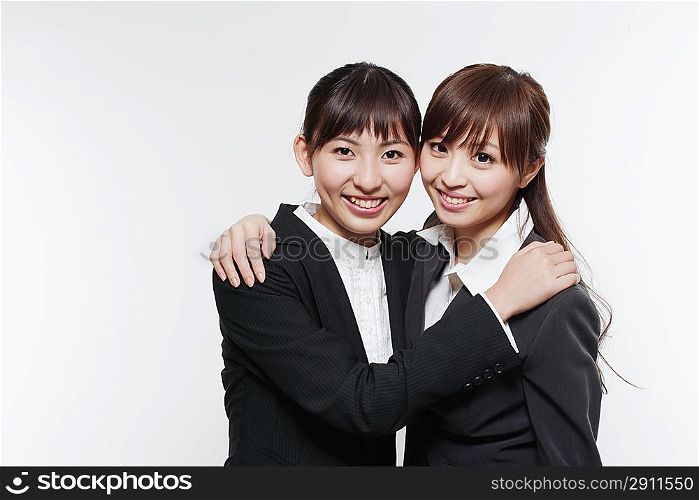 Portrait of two young woman in business suit hugging
